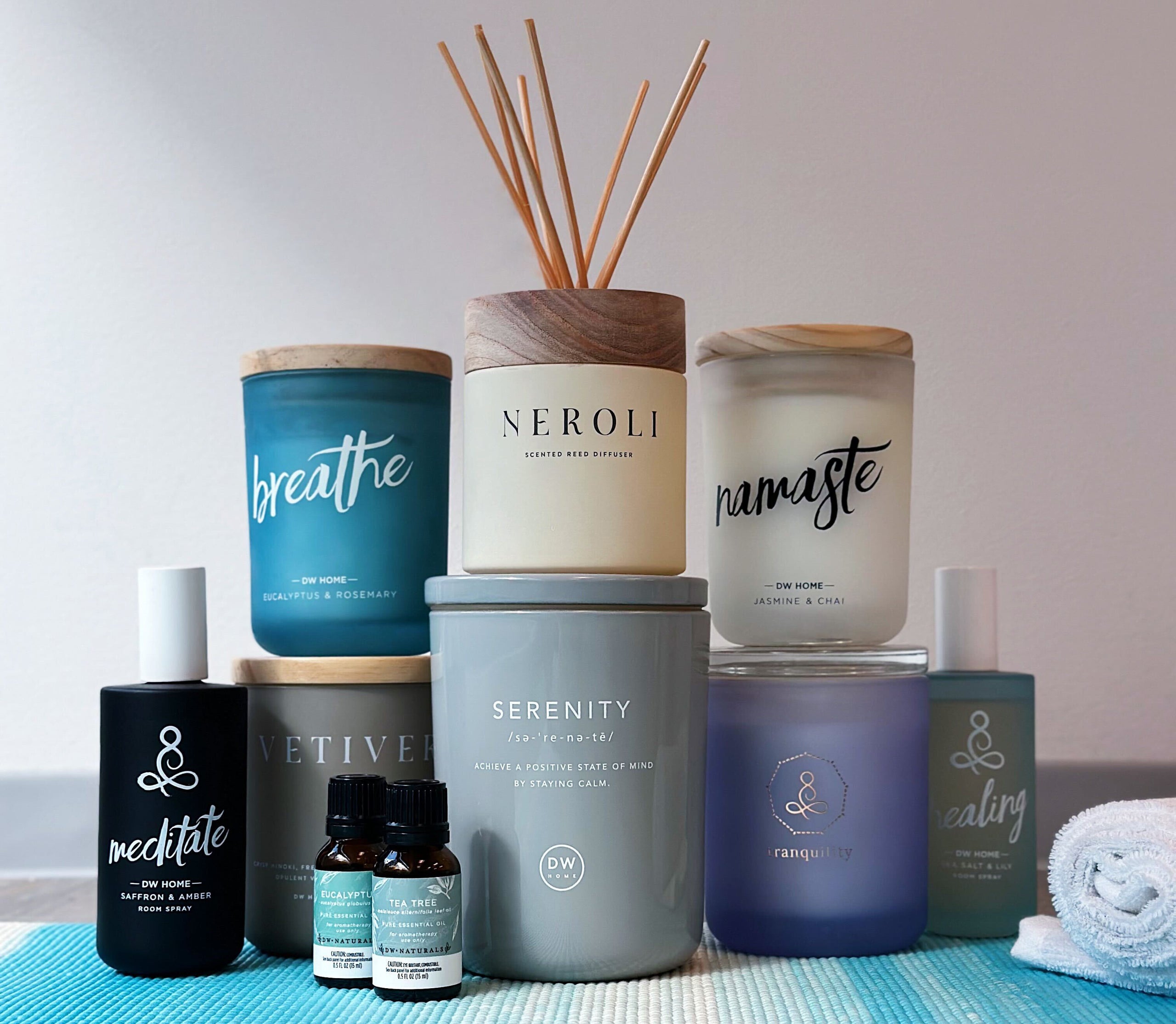 A neatly arranged home shelf with potted plants, scented candles, and reed diffusers.