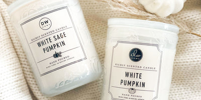 white premium signature candles on a white blanket with white pumpkin accents