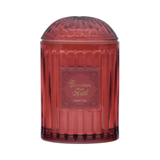 Red transparent candle jar with decorative label on a red background