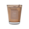 Brown vase candle in a glass container with a label on a brown background